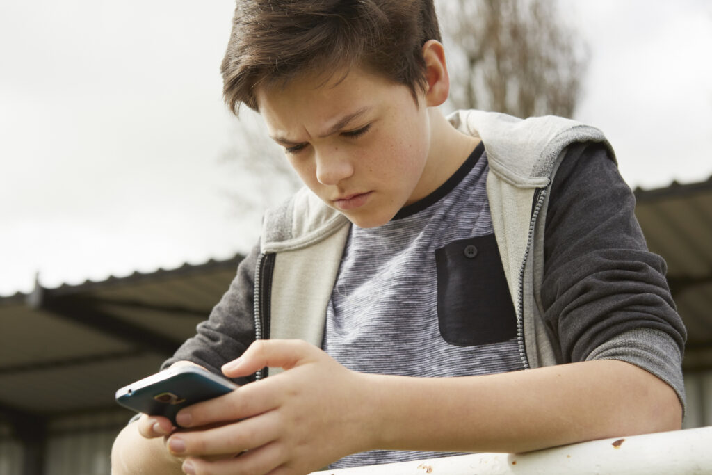 Anxious teenage boy reading smartphone text message
